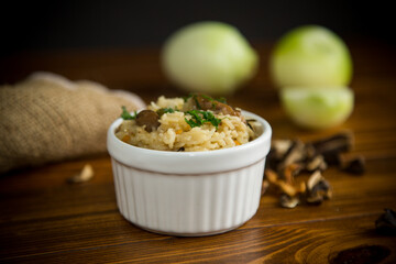 cooked rice with dried forest mushrooms on a wooden table