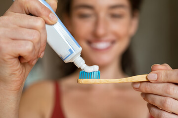 Woman applying toothpaste on bamboo toothbrush - Powered by Adobe