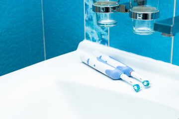 A pair of  electric toothbrush in blue bathroom. Oral hygiene concept at home.