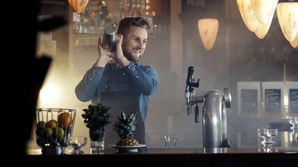 Barkeeper in apron mixing fruit cocktail in smoky bar