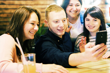 Friends take a selfie in a cafe during a holiday - A group of young people having fun in a bar and taking a selfie - Communication and togetherness concept