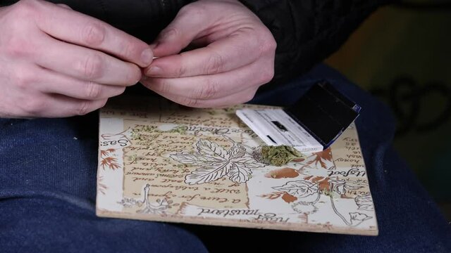 Finishing the shaping on both ends of a marjuana cigarette by hand.