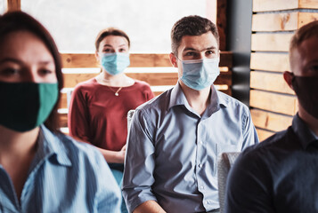 Young people in the new normal wearing masks on their faces are listening to the coach -...