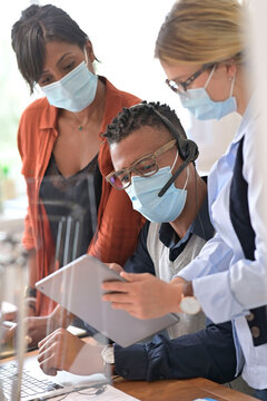 Coworkers in open space office, wearing surgical face mask, 19-ncov pandemic