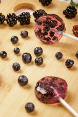 Homemade lollipops made from natural dehydrated bilberry and blackberries on a white wooden background. Healthy vegan vegetarian food with no sweets.