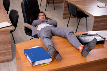Young male employee sleeping at workplace