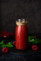 Fototapeta na wymiar Vegetarian raspberry smoothie in a glass bottle on a dark background