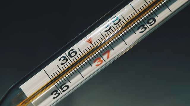 Temperature Rising Shown on a Thermometer. Glass Mercurial Thermometer Shows High Temperature of the Body. Temperature Increase and Decreases on a Thermometer. Black Background. Close Up