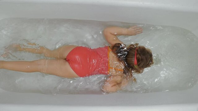 young girl dives in the bath at home, enjoy and learn to dive and swim