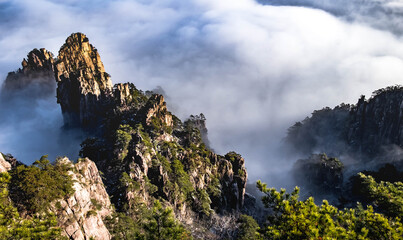 View of the clouds and the pine tree at the mountain peaks of Huangshan National park, China. Landscape of Mount Huangshan of the winter season. UNESCO World Heritage Site, Anhui China.