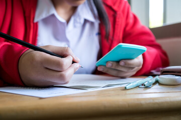 Asian woman student using calculator for used making mathematical calculations in exercise taking exam at school or university, taking in assessment paper on education study.