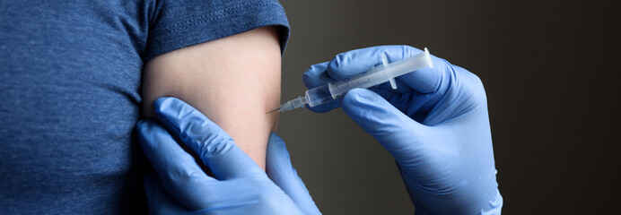 COVID-19 vaccine shot, doctor holds syringe and makes injection to woman patient - obrazy, fototapety, plakaty