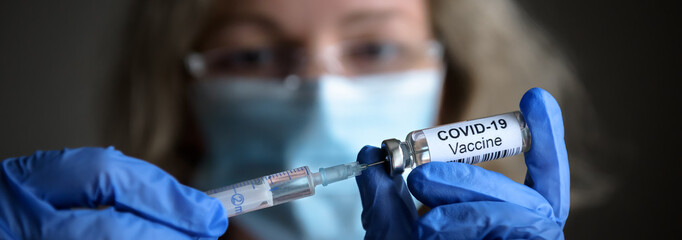 COVID-19 coronavirus vaccine and syringe in doctor’s hands, panoramic banner