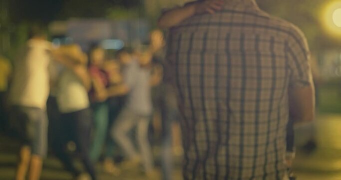 Parel watching street salsa lessons with a little child on his hands, rear view