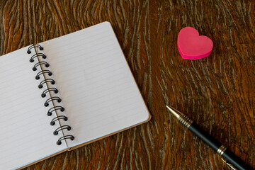 notebook, pen and heart on rustic wooden table. Valentine's Day. space for text.