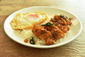 spicy fried crispy chicken with basil leaf and chilli topping egg on rice in plate