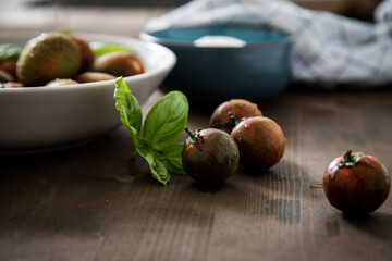 Gestreifte bunte Tiger Tomaten in Schale mit Mozzarella und Basilikum mit Geschirrtuch auf Holz 