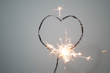 Heart shape sparkler
burning on a gray background with valentine background concept.