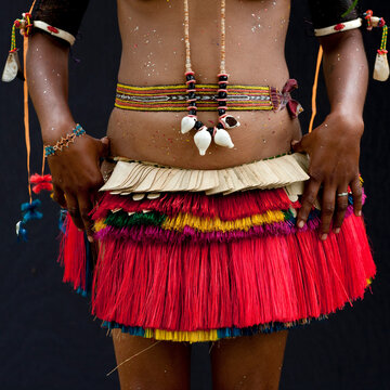 Woman wearing a traditional red skirt made with pandanus and banana leaves, Milne Bay Province, Trobriand Island, Papua New Guinea