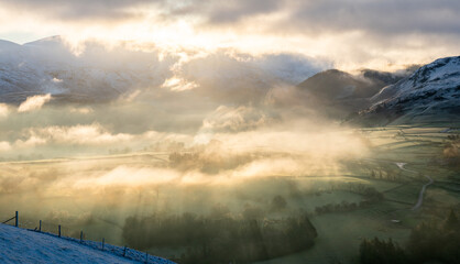 Atmospheric sunlight shining through early morning mist in the Lake District