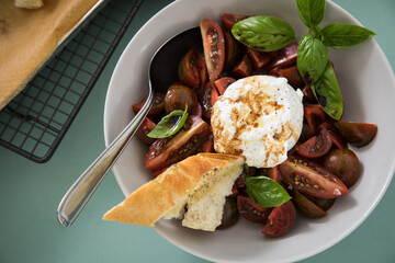Caprese Tomaten Mozzarella Salat mit gestreiften bunten Tiger Tomaten in Schale mit Basilikum mit ...
