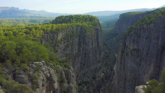 A man and a woman are sitting on the edge of the Tazy canyon in National Park on Manavgat, Antalya, Turkey. Aerial view 4K.