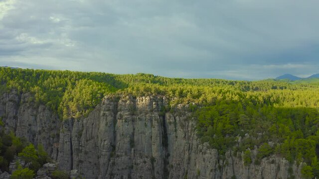 A man and a woman are sitting on the edge of the Tazy canyon in National Park on Manavgat, Antalya, Turkey. Aerial view 4K.