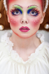Closeup portrait of a caucasian female model with creative fairy clolorful makeup, looking up.