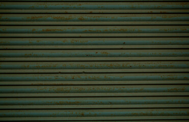 Old green rusting metal security shutters full frame background texture with horizontal slats