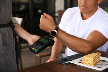 Man making payment with smart watch in cafe, closeup