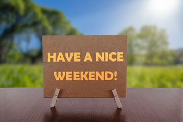 Have a nice weekend text on card on the table with sunny green park background.