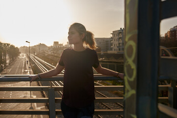 Blond woman leans stands on a railway bridge