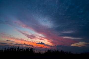 Obraz premium A marvelous photo of colorful and cloudy sunset scenery that has a sea under it.