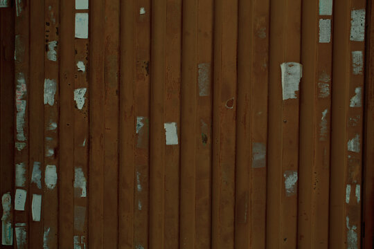 Wooden wall or fence with poster remnants and vertical planks in a full frame view © danr13
