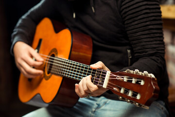 Hands of man playing guitar. Guitarist holding an acoustic guitar. Handsome man playing guitar at the pub.