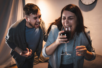 drunk man screaming at alcohol-addicted wife holding wine glass with closed eyes