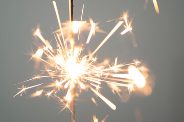 Sparkler lit burning down on a gray background 