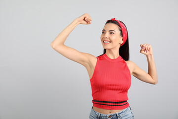 Strong woman as symbol of girl power on light grey background. 8 March concept