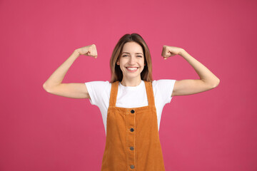 Strong woman as symbol of girl power on pink background. 8 March concept