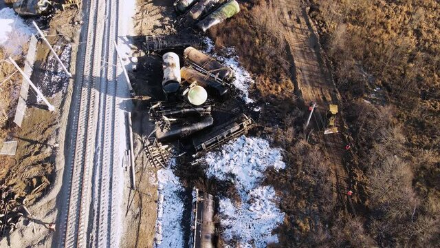Train wreck on the railroad, scattered tanks from collision, bulldozer rides. Aerial view of the accident - a crash with damaged wagons lying next to the rails. Rescuers carry out repair work.
