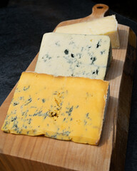 A selection of three cheeses on a wooden platter on an outdoor table in Cartmel, Cumbria
