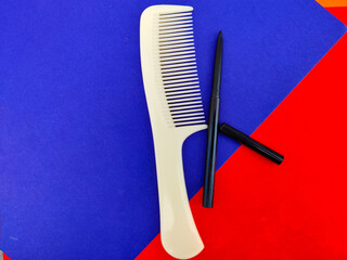 One comb and kajal pencil isolated on red and blue background