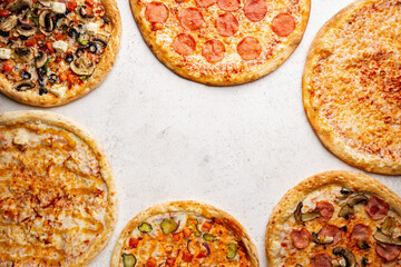 Flat-lay of different types of pizza and red wine over white table, top view. Fast food lunch, celebration, pizza party