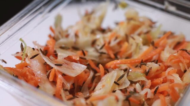 Cabbage and carrot salad sprinkled with cumin. Healthy food. The tray rotates. Selective focus
