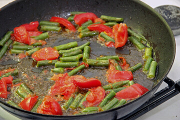 Tomato and green beans roasted on the black frying pan