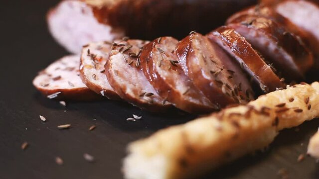 Sprinkle cumin on sliced sausage and bread. The tray rotates. Selective focus