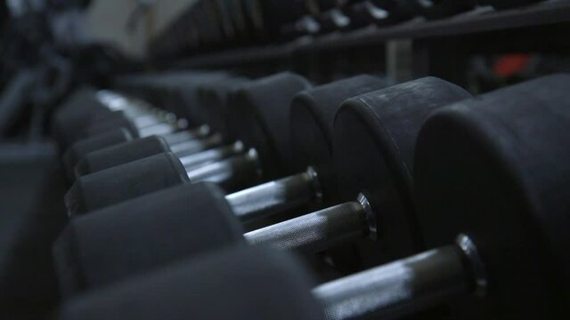 Focus shift on row of heavy dumbbell weights in a dark gym