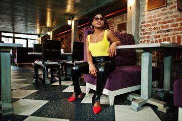 Fototapeta na wymiar Stunning African American women in yellow top and black leather pants pose at pub.