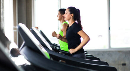 attractive young woman and female running on treadmill  machine at gym sports club. Fitness Healthy lifestye and workout at gym concept.