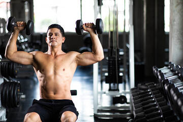 Young Man Naked bodybuilder exercising lifting with dumbbell at gym. .Gym equipment and sport...